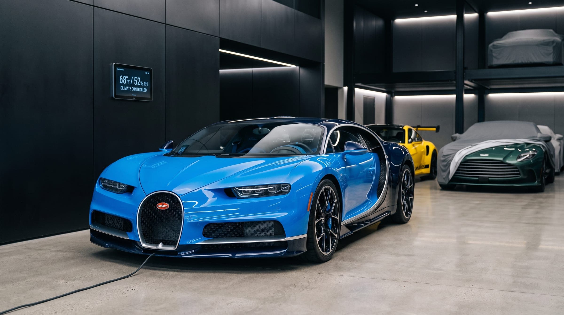 Blue Bugatti Chiron on charge in a private storage bay beside covered collector cars