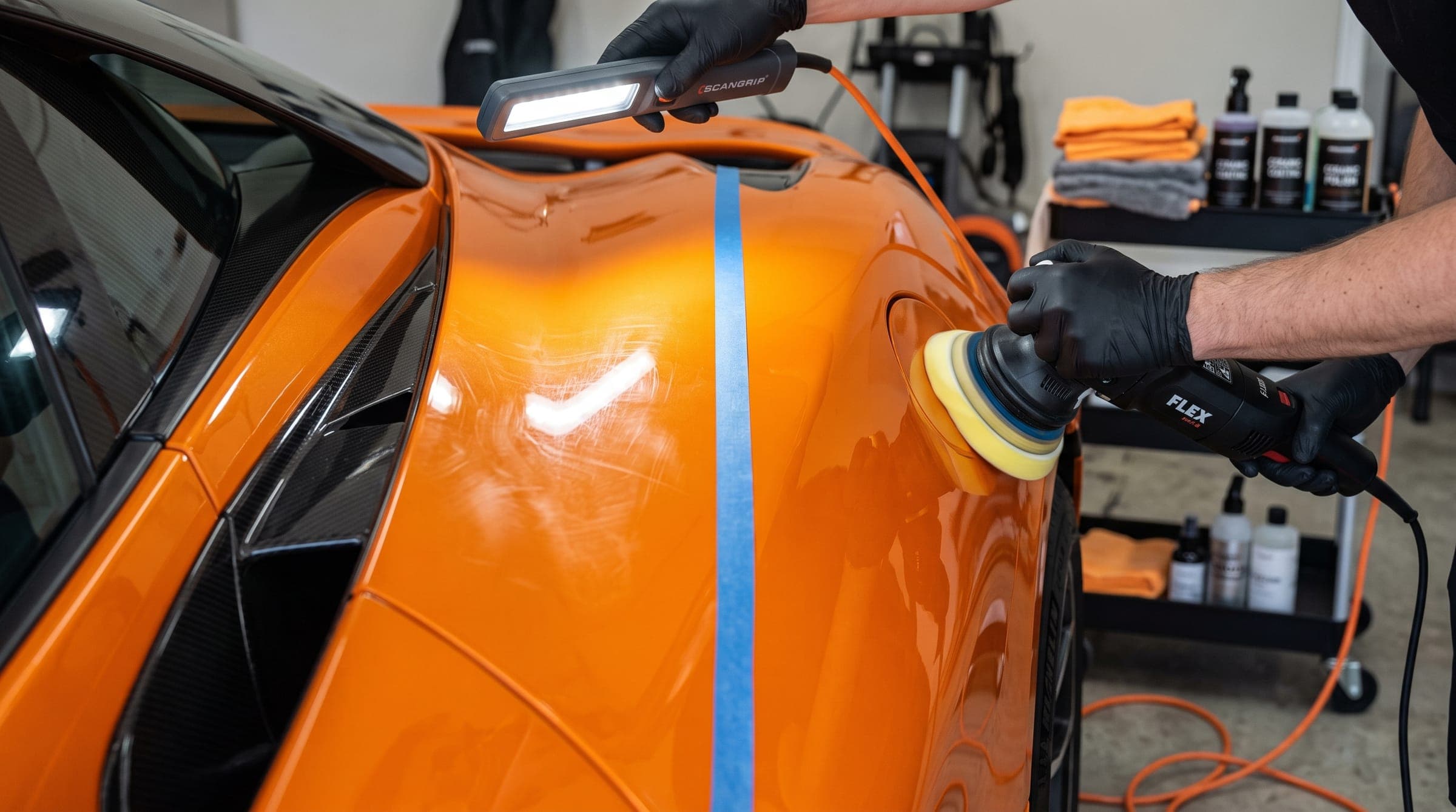 Detailer machine-polishing the paint of an orange supercar