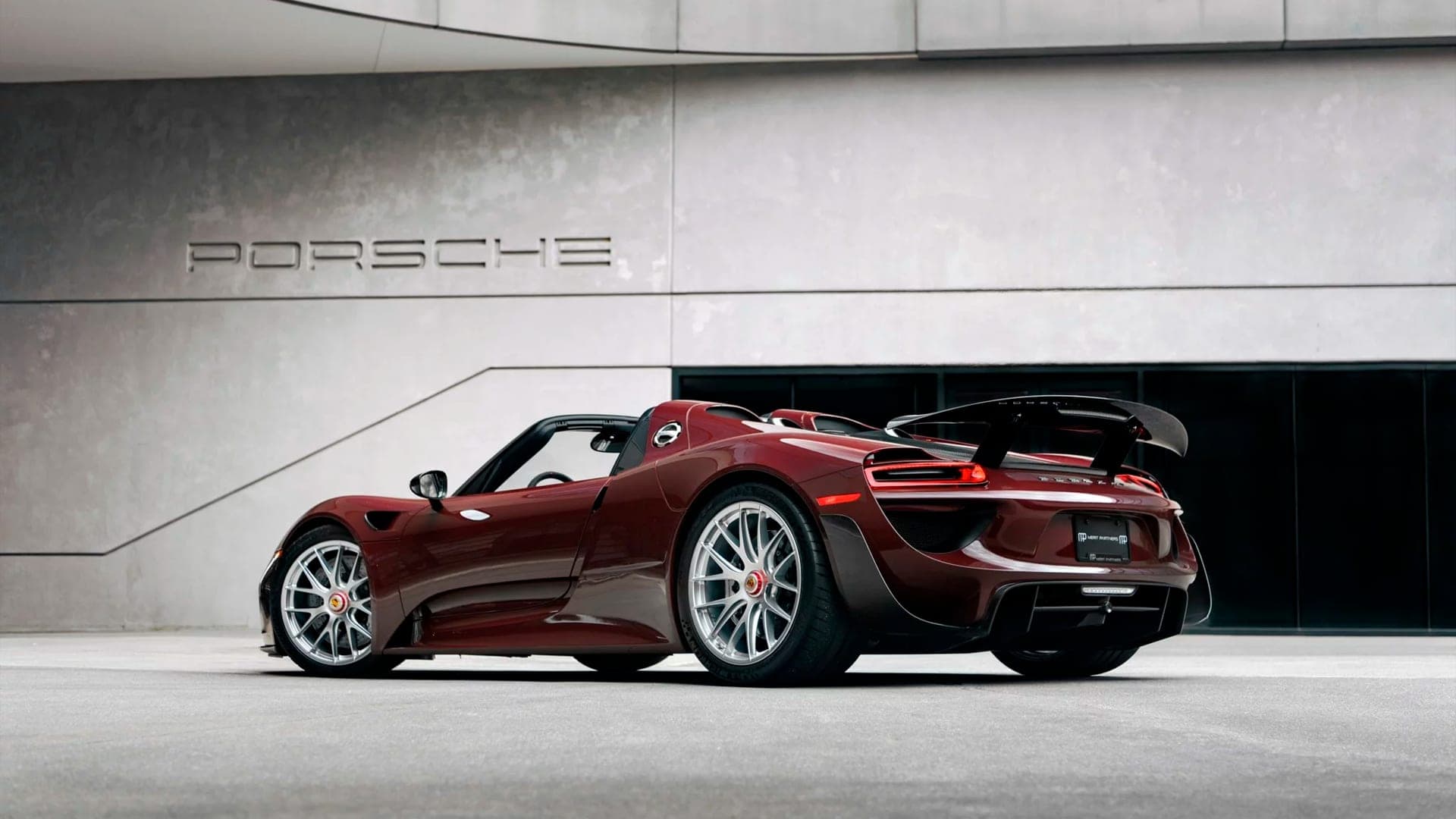 Burgundy Porsche 918 Spyder rear three-quarter view with wing raised