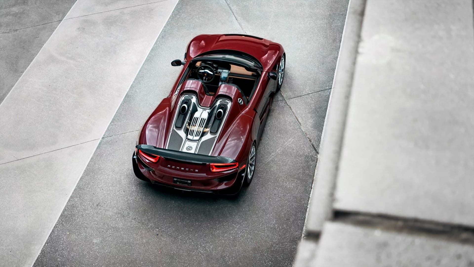 Aerial view of a burgundy Porsche 918 Spyder with open roof