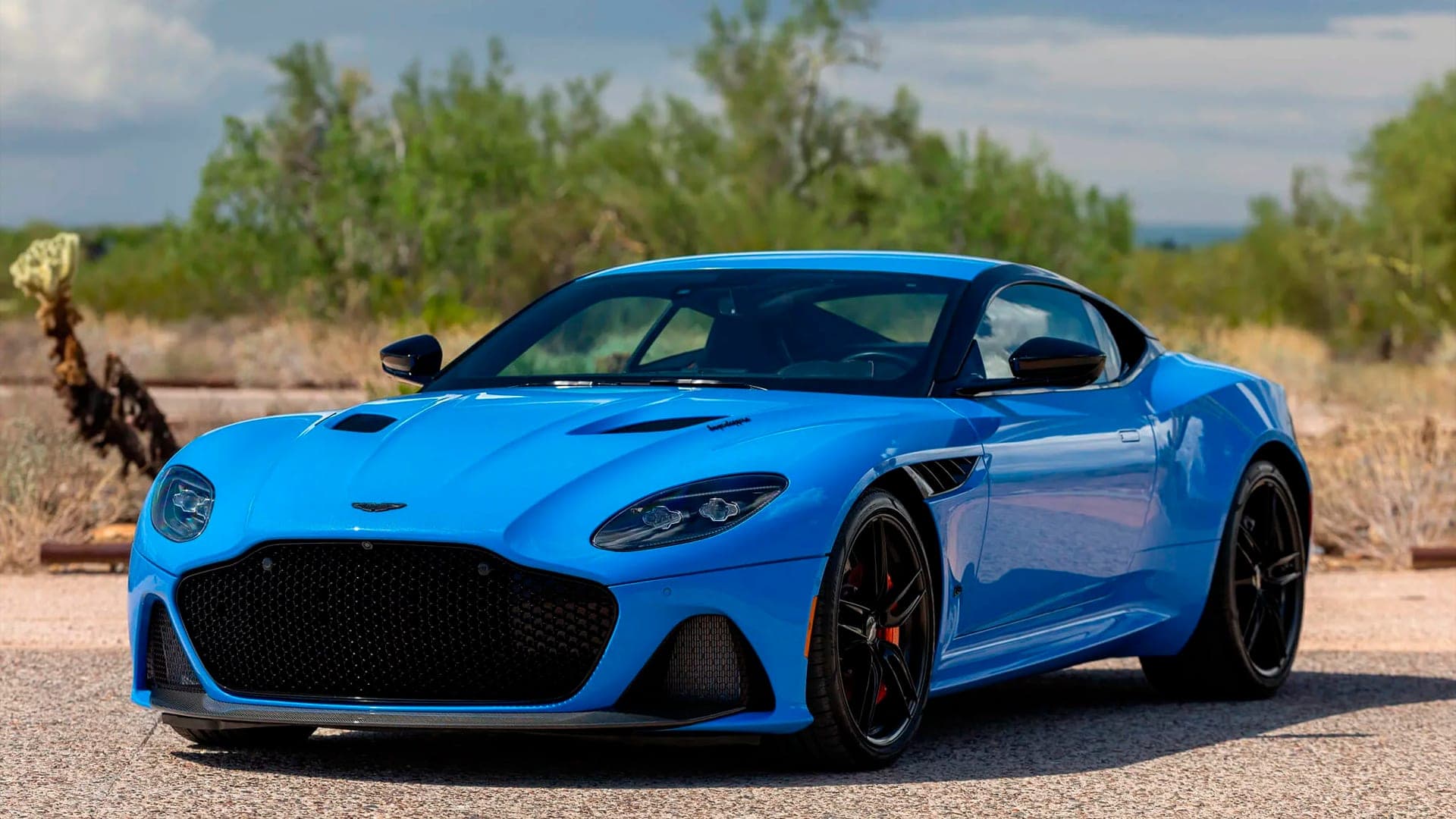 Blue Aston Martin DBS Superleggera front three-quarter view in the desert