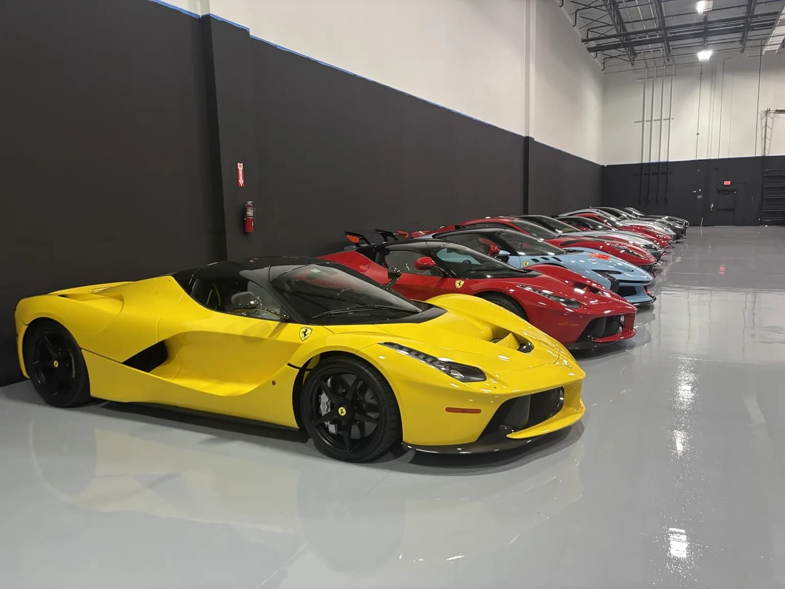 Yellow LaFerrari Aperta leading a long row of Ferraris along the storage wall