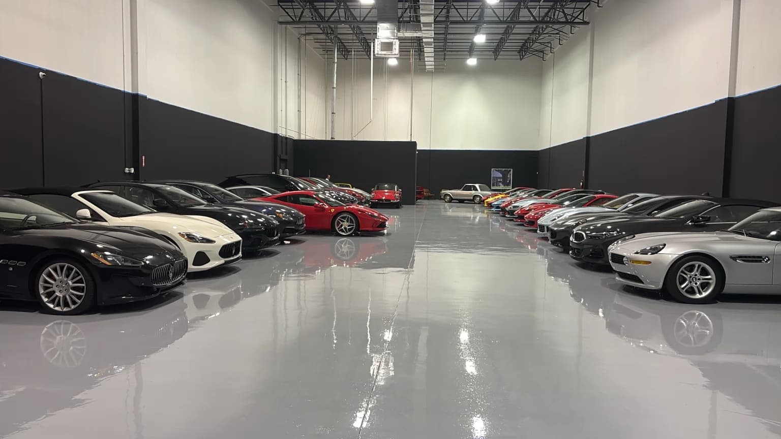 Two rows of collector cars on the polished grey floor of the DGarage storage hall