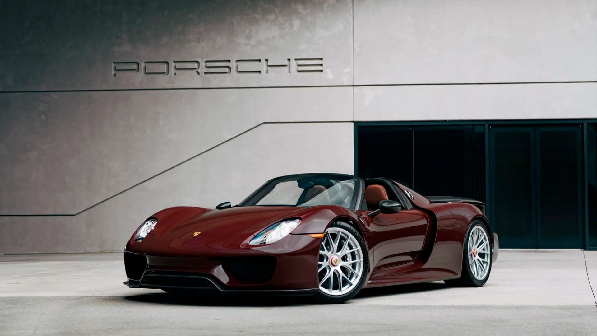 Burgundy Porsche 918 Spyder front three-quarter view beneath the Porsche lettering
